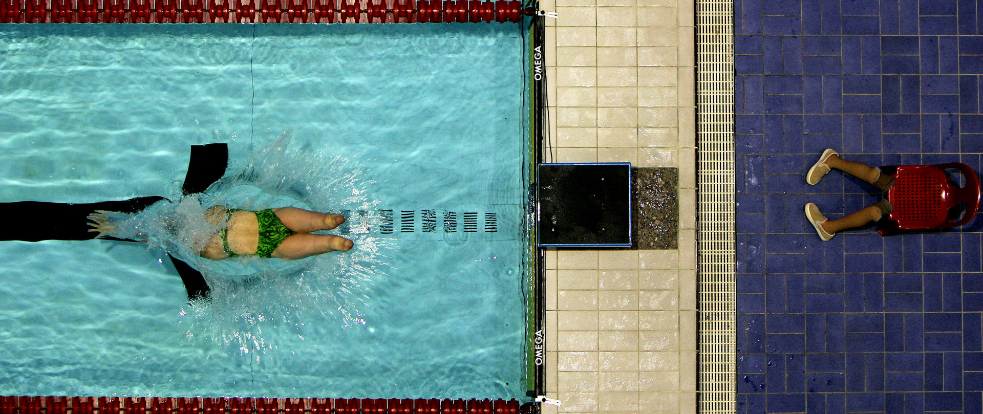 Fifteen year old Paralympian Jessica Long diving into the pool as her prosthetic legs sit on the side.