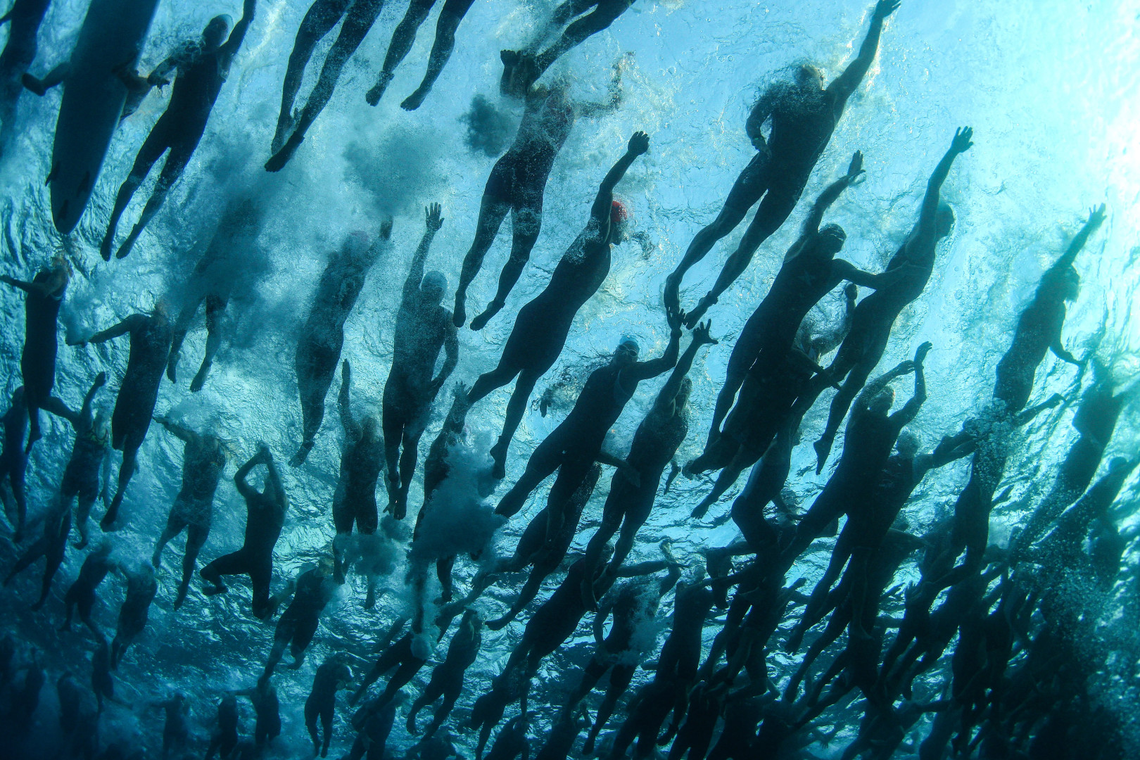 Swarm of swimmers thrashing through the water at an Iron Man contest.