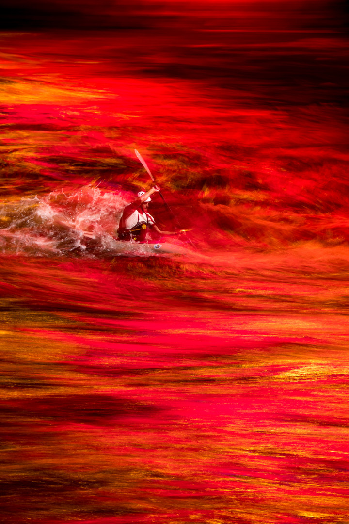 Kayaker travelling through lava-like water.