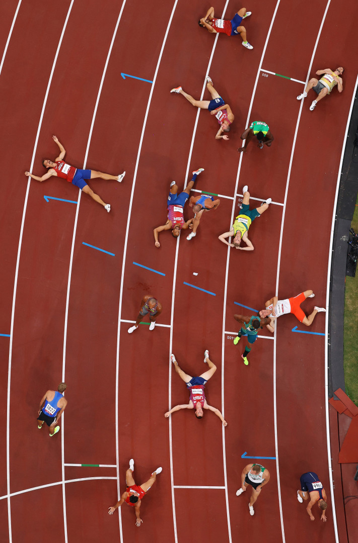 Birdseye view image of athletes collapsed on track in exhaustion at the end of a race. 