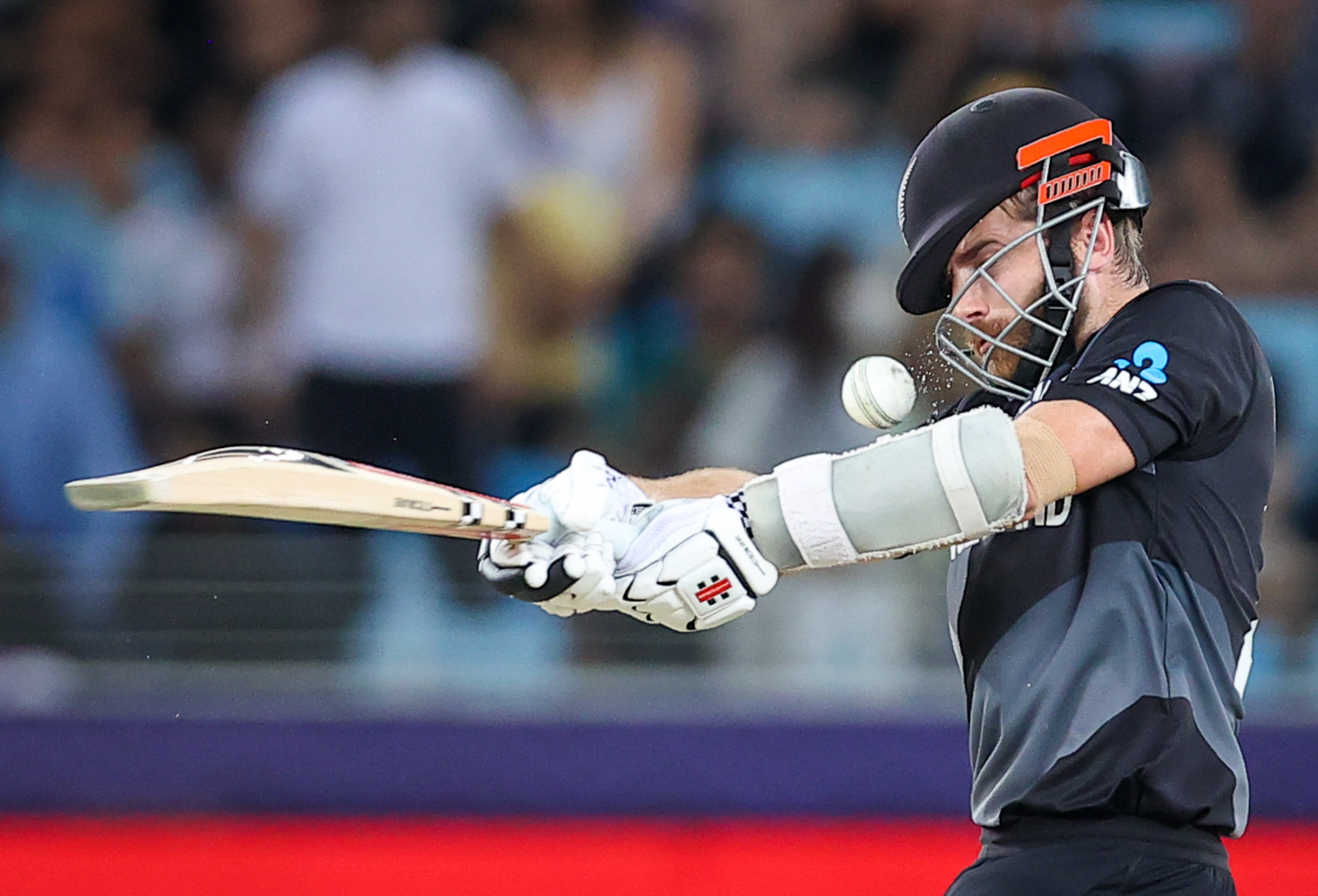 Close up of New Zealand cricketer missing hit as ball smashes against safety helmet.