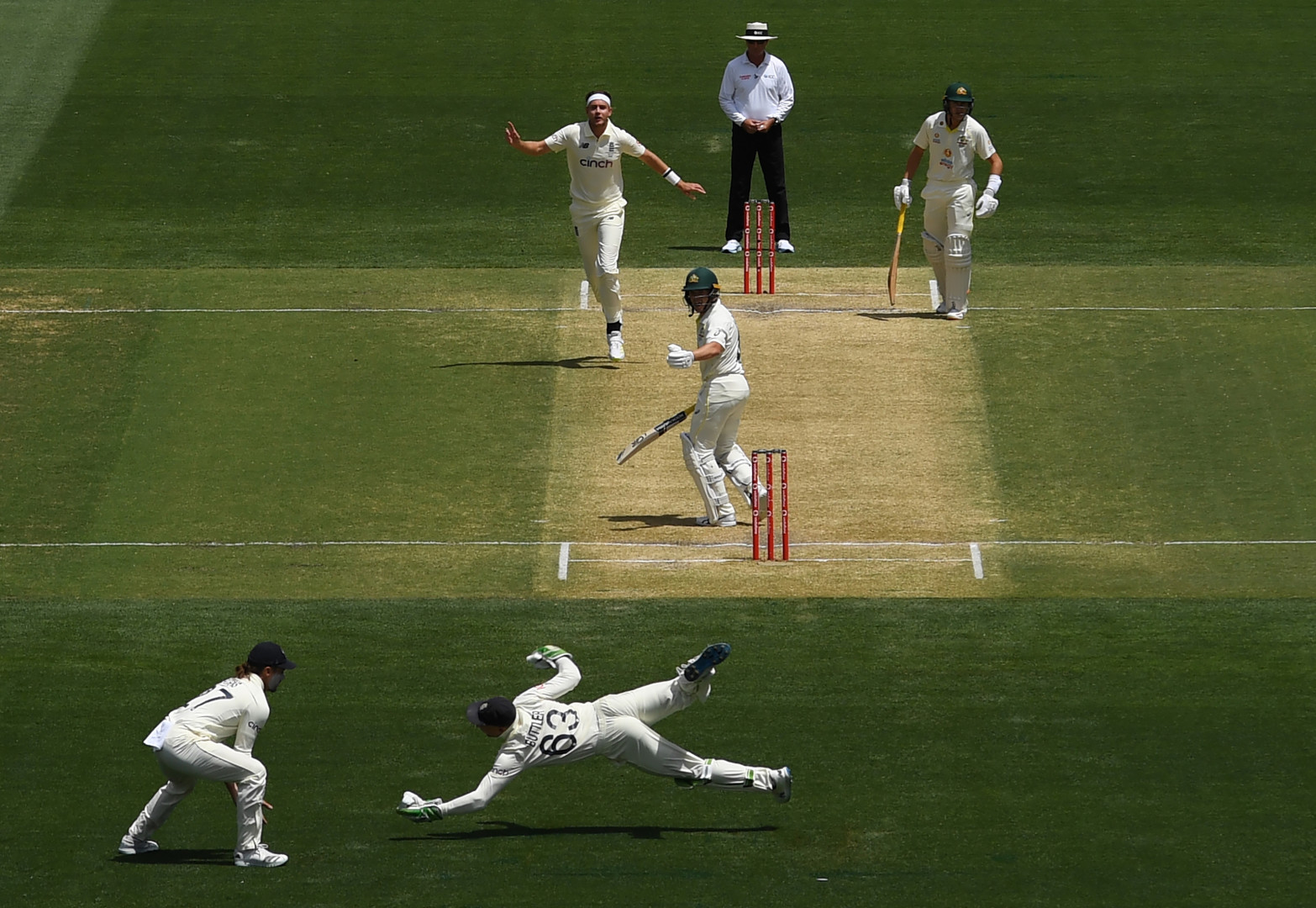 Buttler launches himself to the green to catch cricket ball for England team against opposition.
