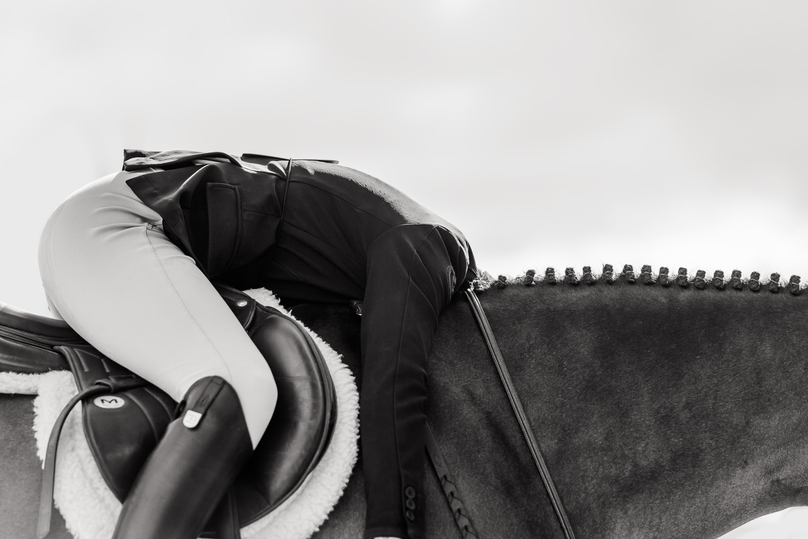 Close up image of jockey slumped over horse after race.