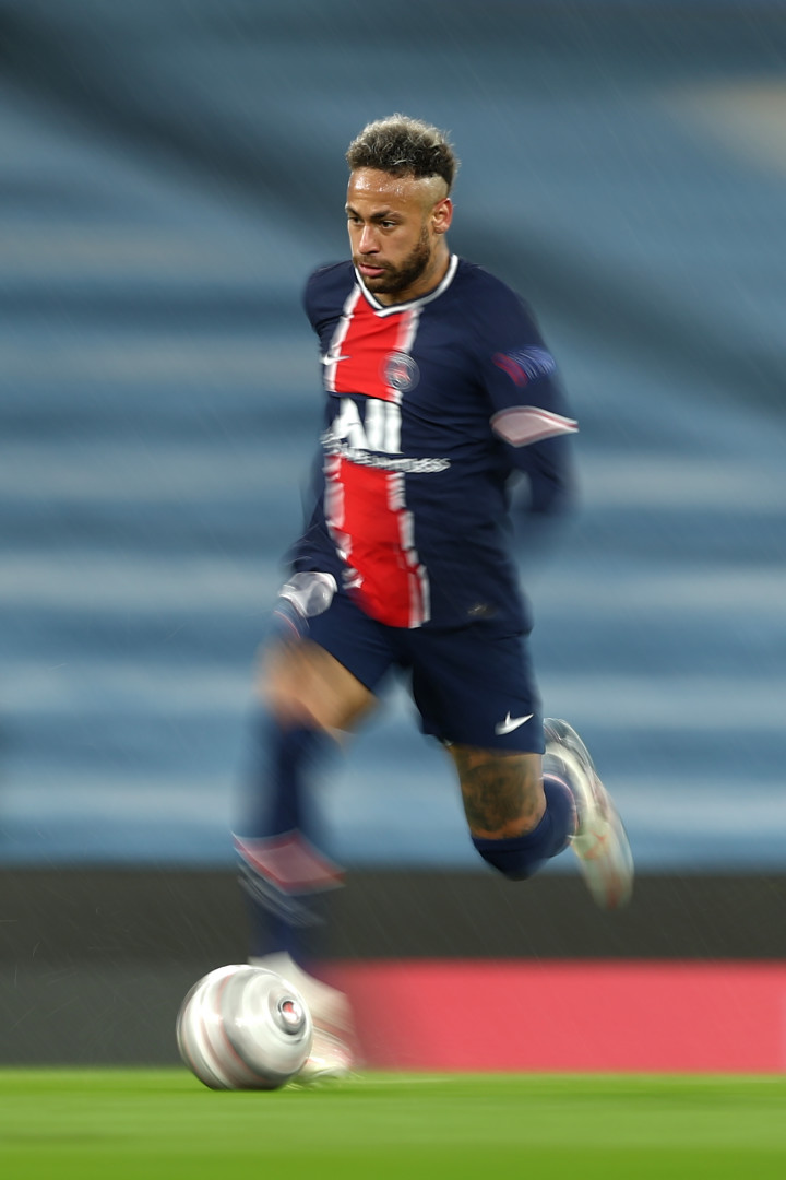 Portrait image of footballer, Neymar, running in motion with a football.