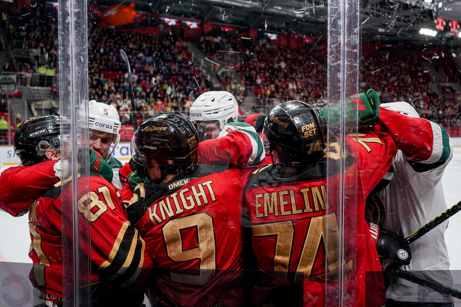 Hockey team celebrate point up against the safety glass.
