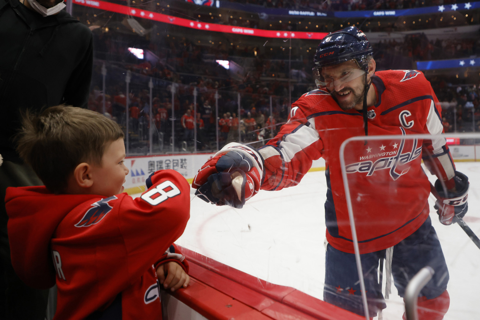 Hockey captain fist bumps young fan through the safety glass.