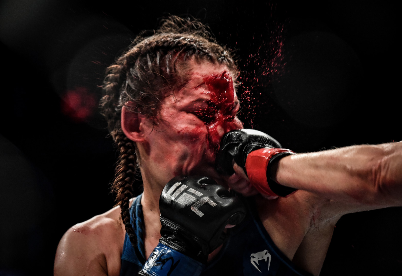 Sucker punch to the mouth in a female kickboxing match as blood splats from face.