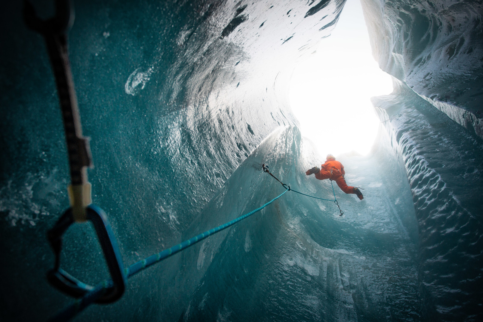 Man climbing up through a cavernous ice tunnel in Olympic competition.