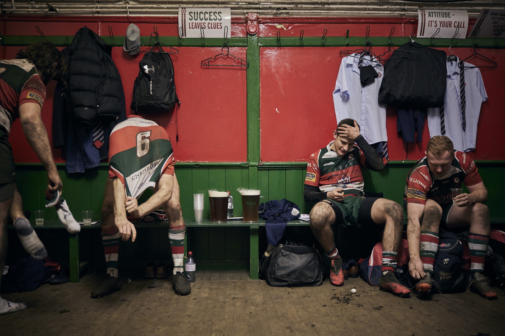 Four muddy rugby team mates in the changing rooms after a game.