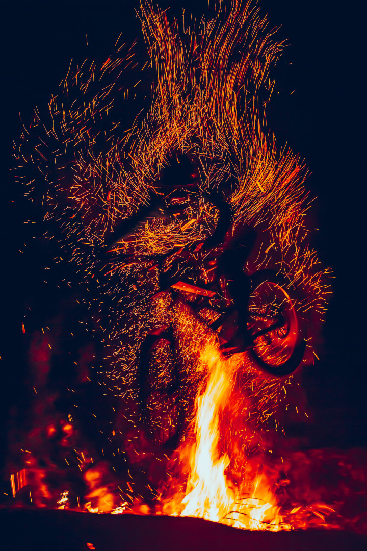 Figure of BMX rider bursting through flames and sparks of a fire.