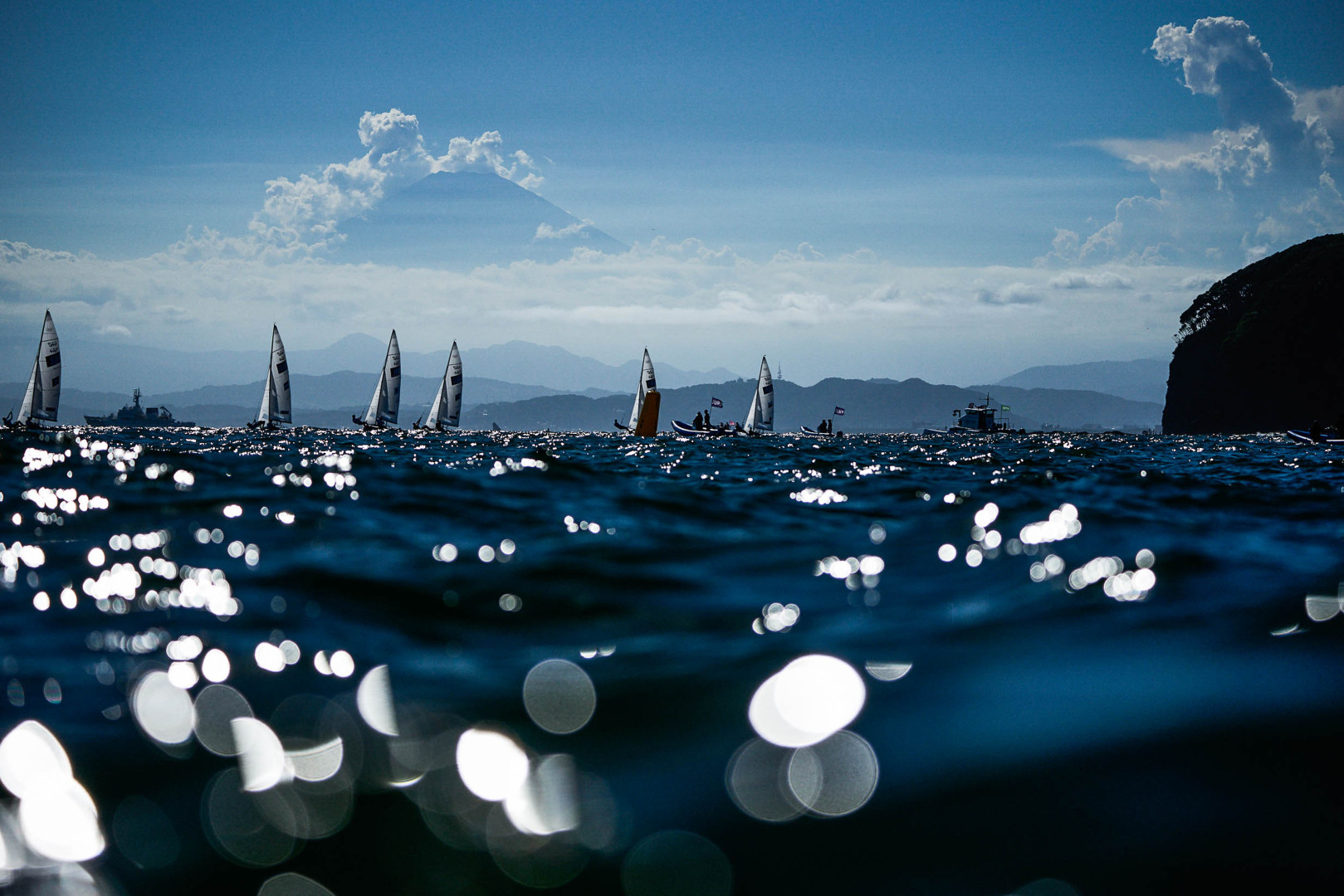 Boats sailing in the distance through the glistening deep blue sea.