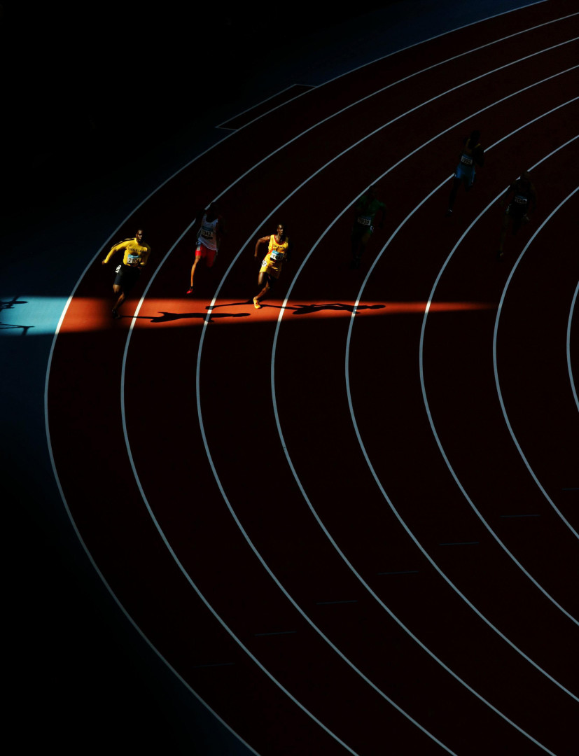 Two athletes run into a patch of light while running the bend of the men's 200m heat at the Commonwealth Games.