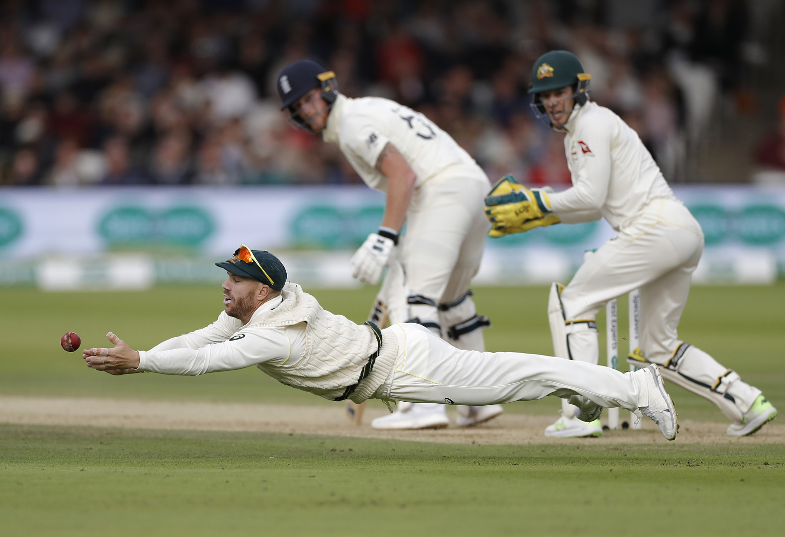 Full stretch from an Australian cricketer as he dives to catch the cricket ball.