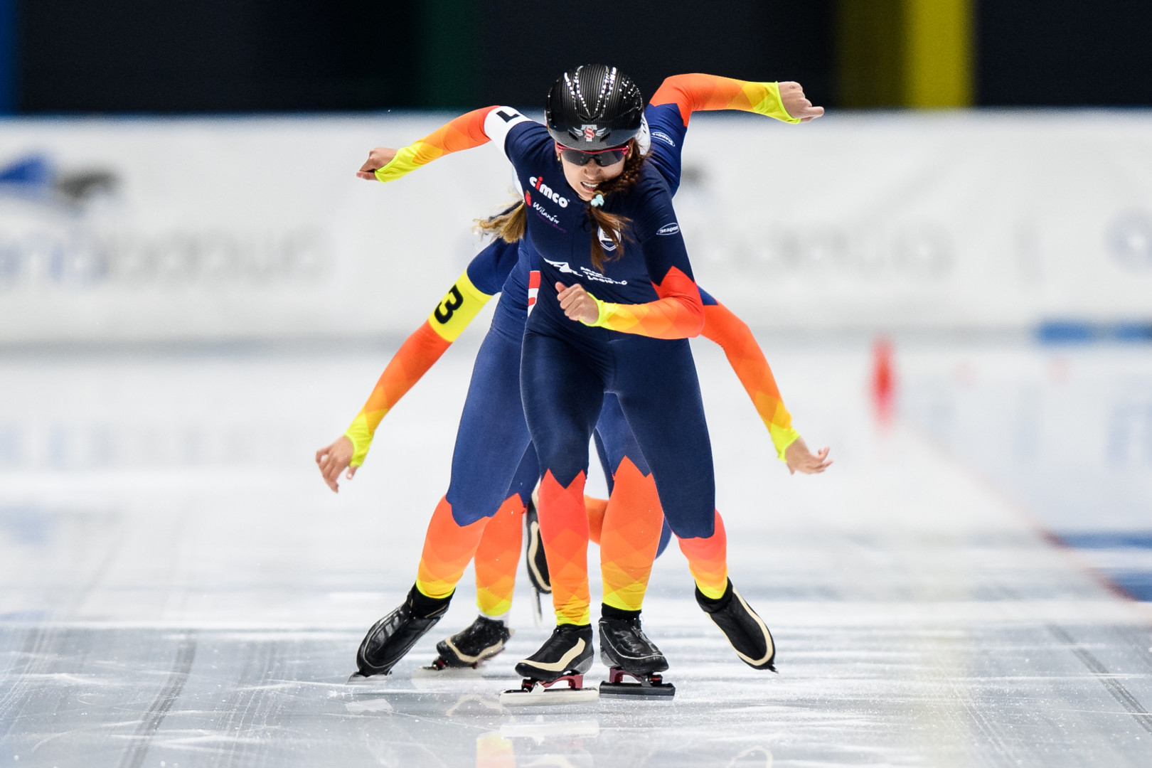 Team of female Speed skaters racing down the track towards the camera.