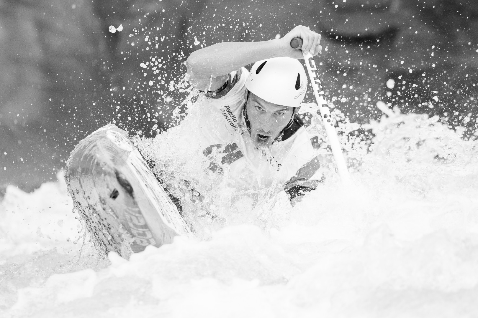 Black & White photograph of a Canoe Slalom athlete splashing through the water.