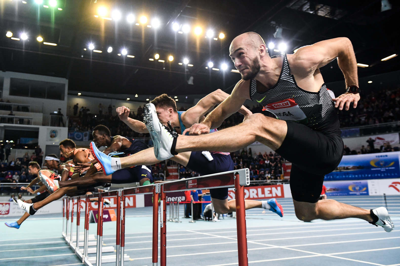 Hurdle athletes jump the hurdles in synchronisation.