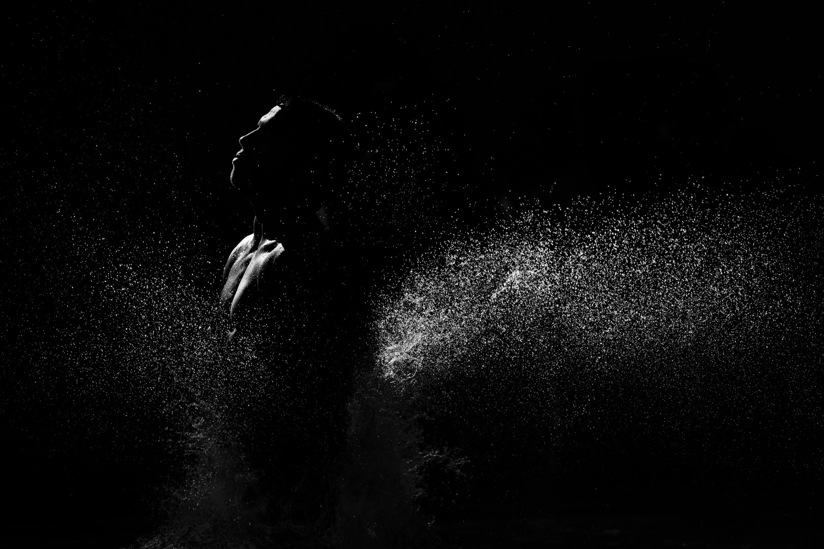 Black & White photograph of the water being splashed by a swimmer, highlighted by the light.