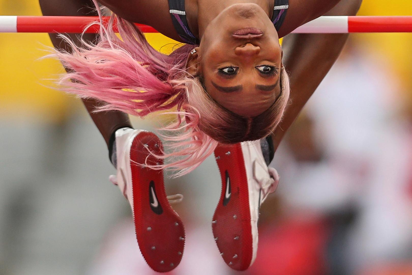 Close up photograph of a female athlete mid high jump as she appears split in half.