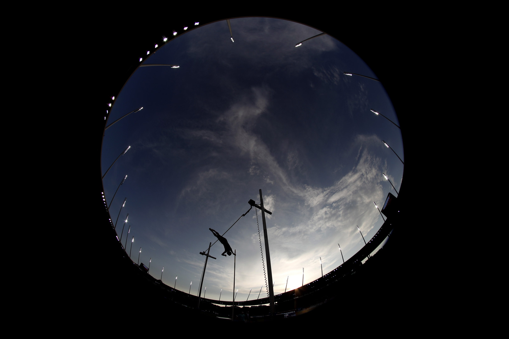Fisheye photograph of an athlete mid pole vault during competition.