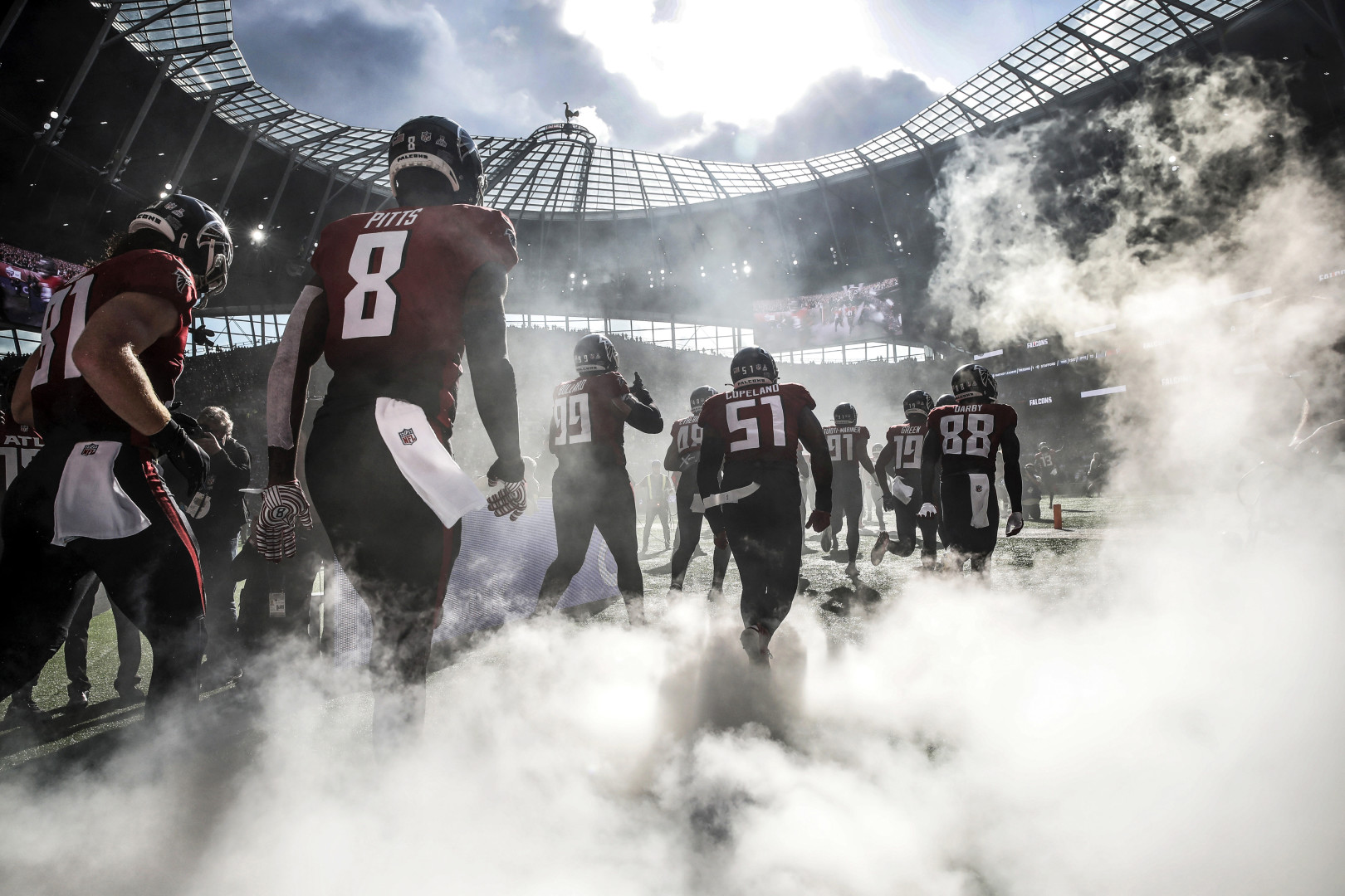 The backs of an American football team emerging from the tunnel onto the pitch.