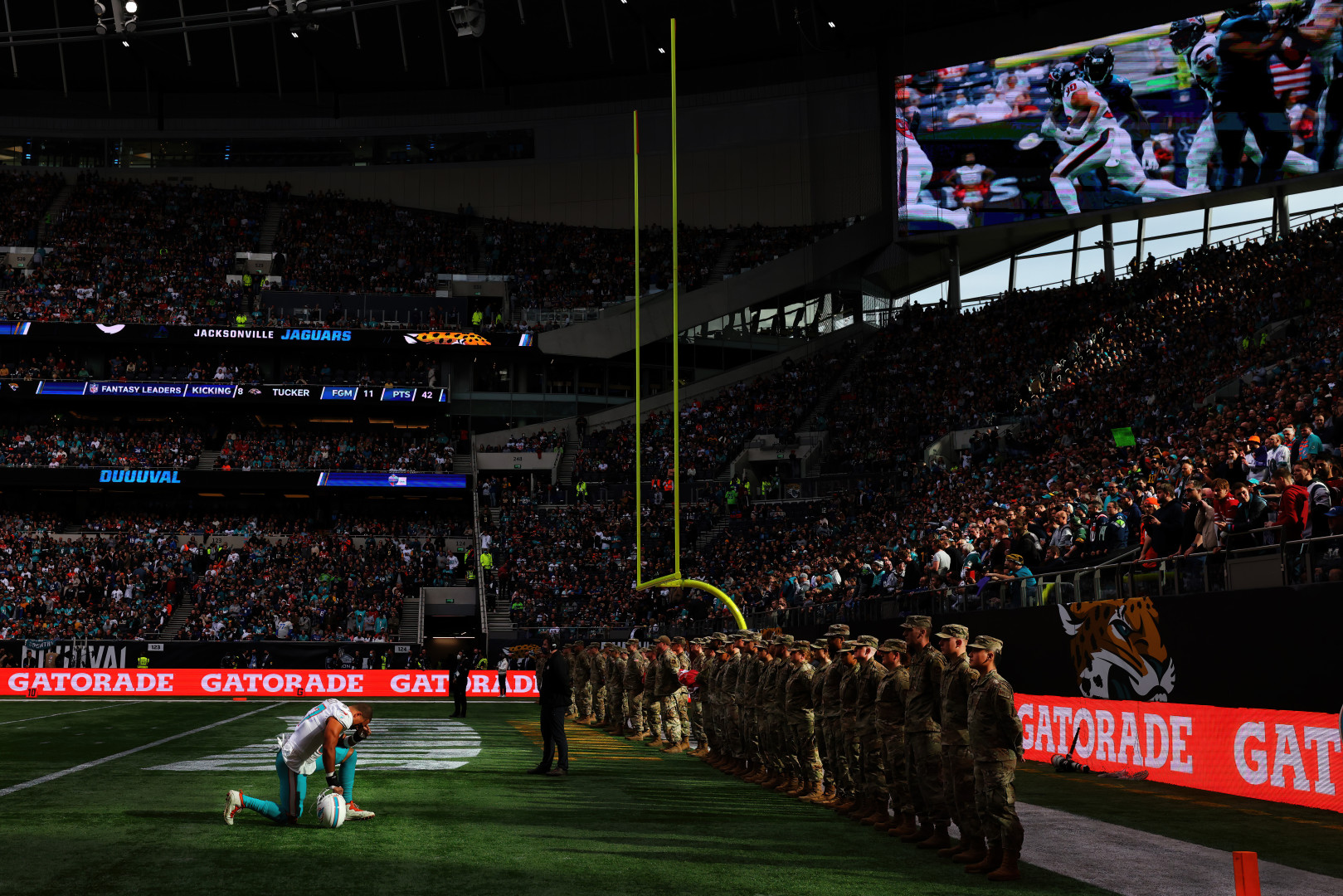 NFL player knelt with his head bowed in front of a row of Armed Forces soldiers before game. 
