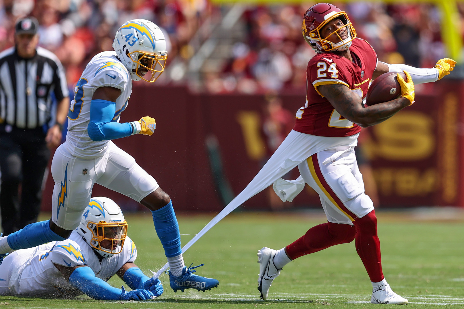 A player on the floor clinging on to an opponents shirt and ripping it.