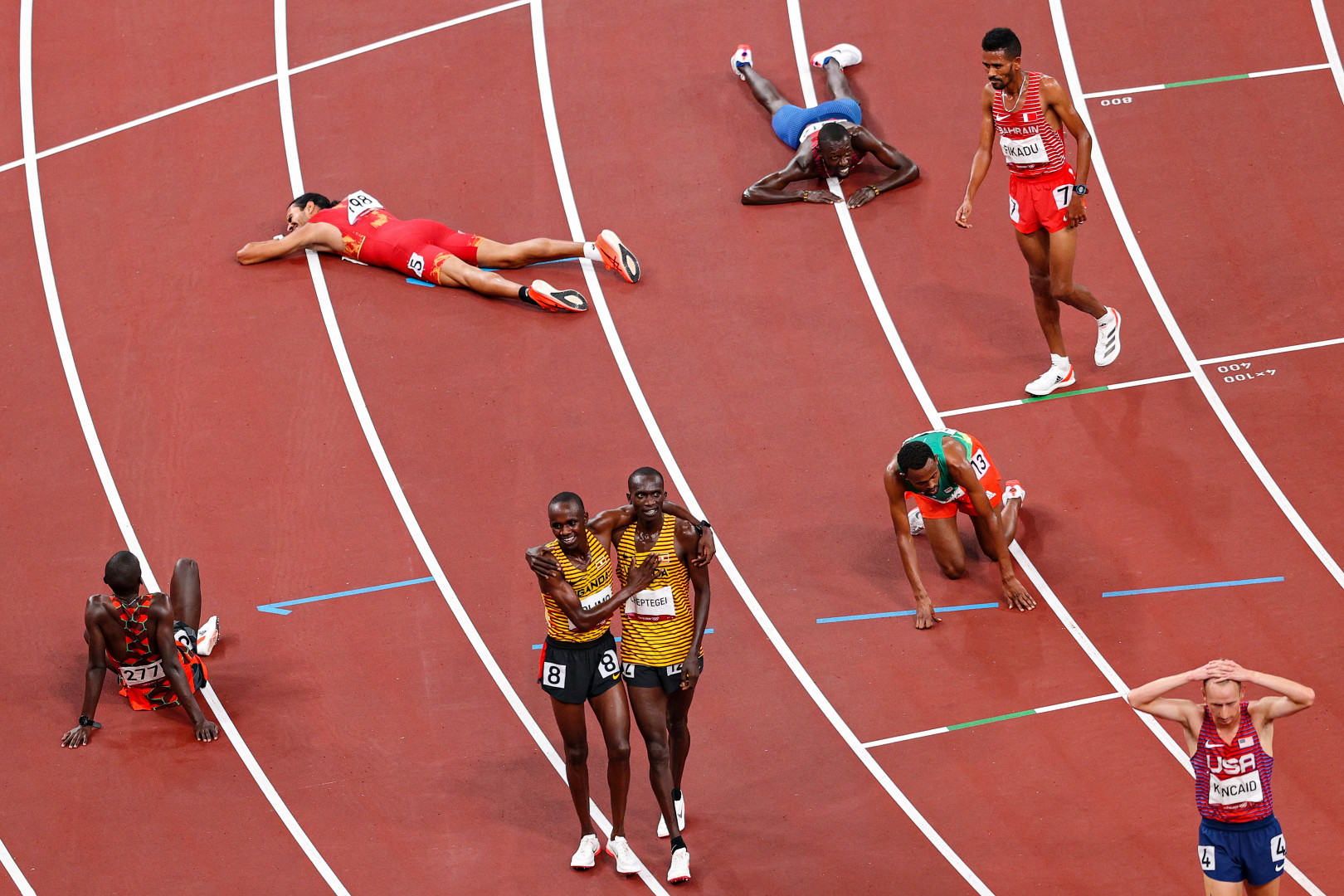 Photograph from the stands as tired athletes lie collapsed on the floor after race, whilst some celebrate.
