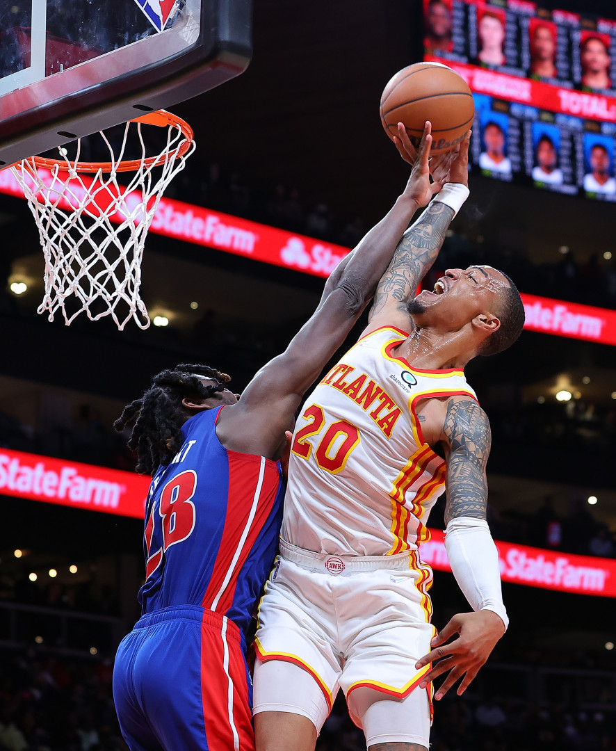 Basketball player in a blue kit, blocking the shot of an opposing player.