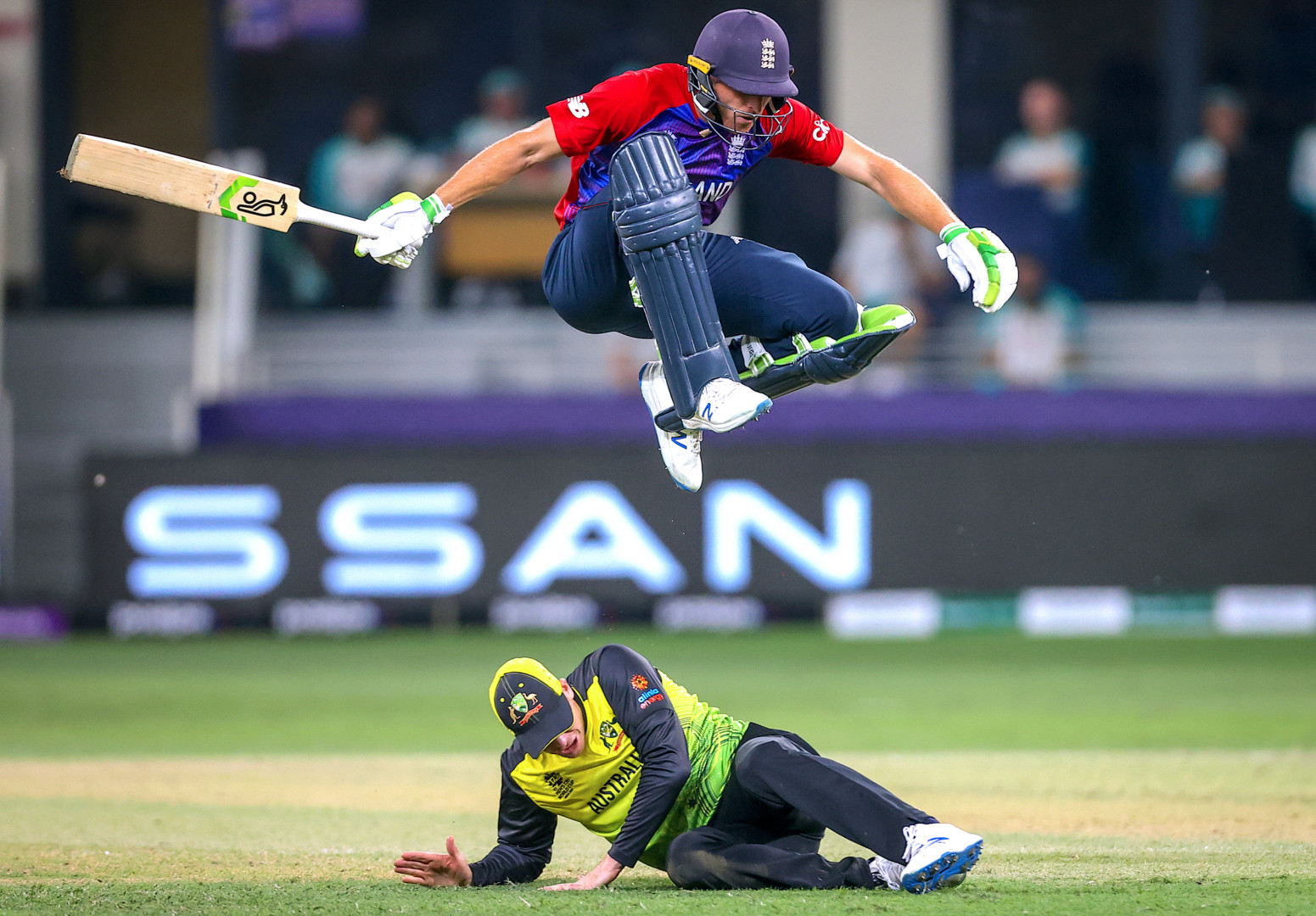 England batter jumping over sliding Australian fielder.