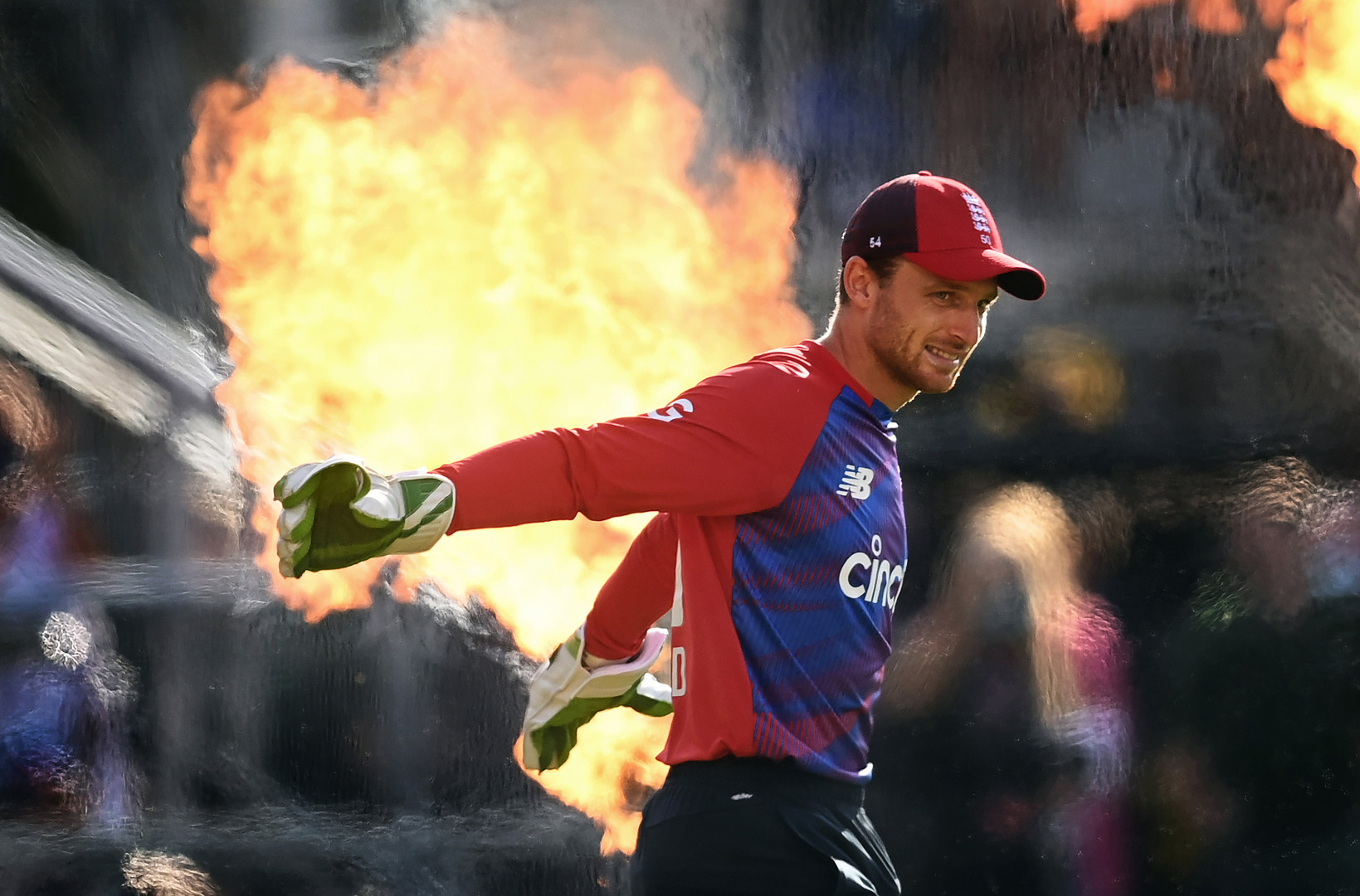 England cricketer walking out onto the field as flames burst high behind him.
