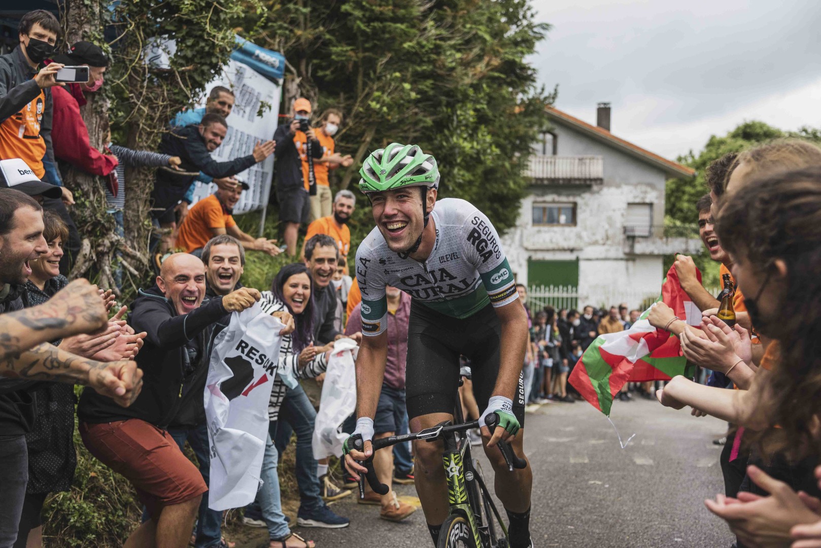 Fans cheering on a road cyclist as he rides through the middle of them.