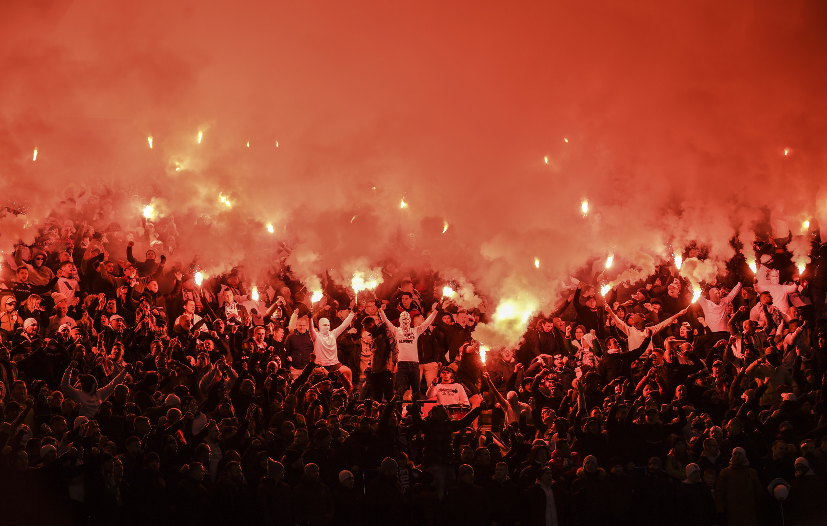Crowd of Legia Warsaw fans holding flares after game against Leicester City.