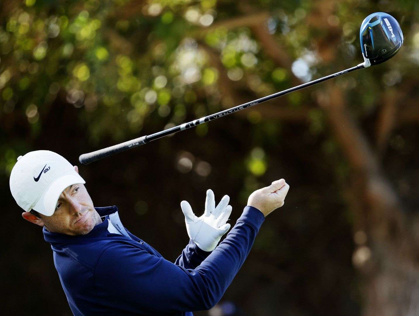 Rory McIlroy trying to avoid getting hit by his own golf club as it slips from his grip.