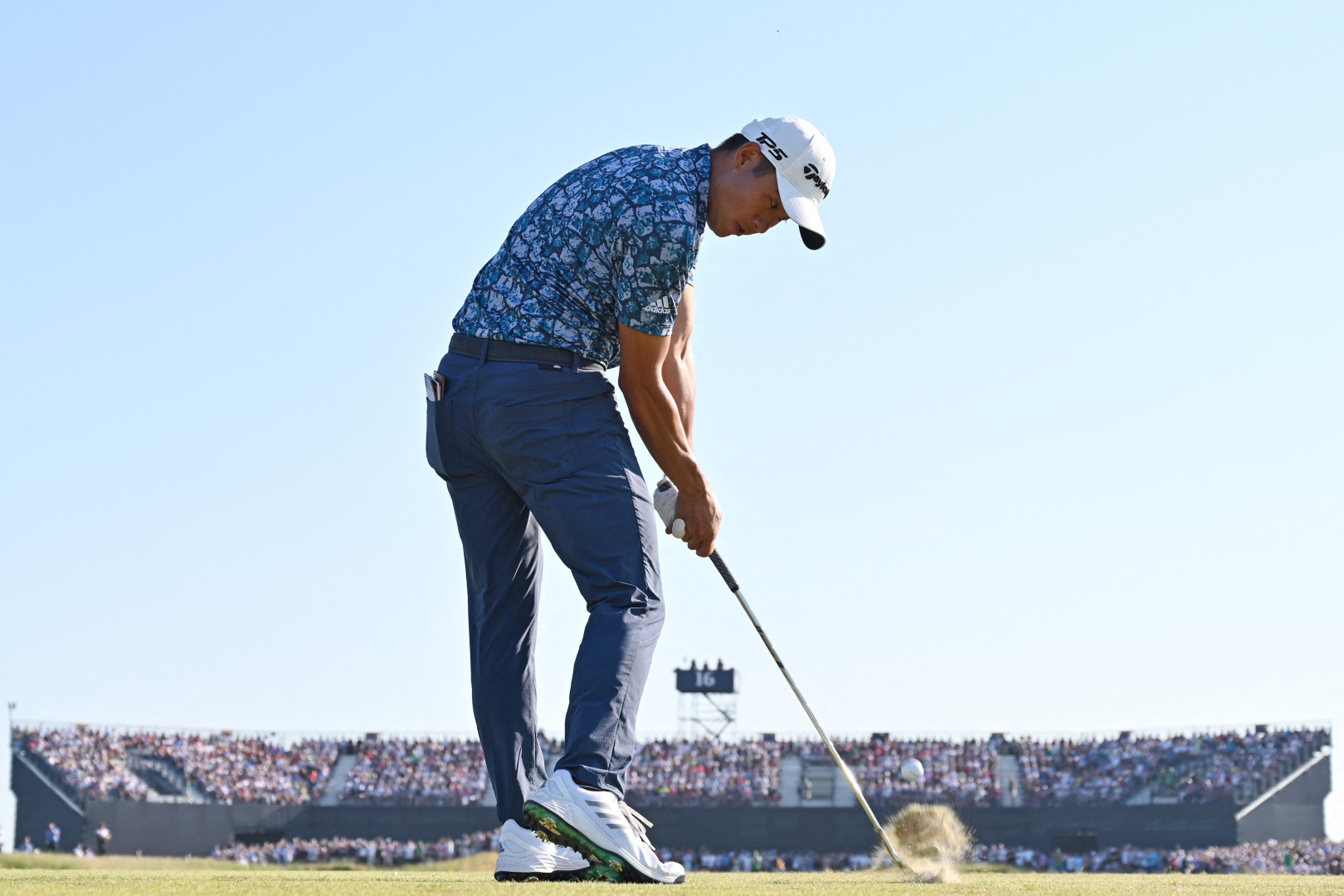 Golfer concentrating on putting the golf ball off of the sandy green.