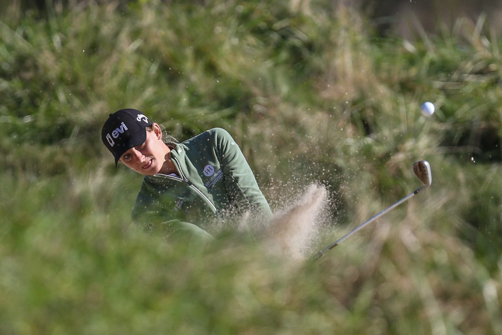 Female golfer hitting golf ball out of the sand bunker.