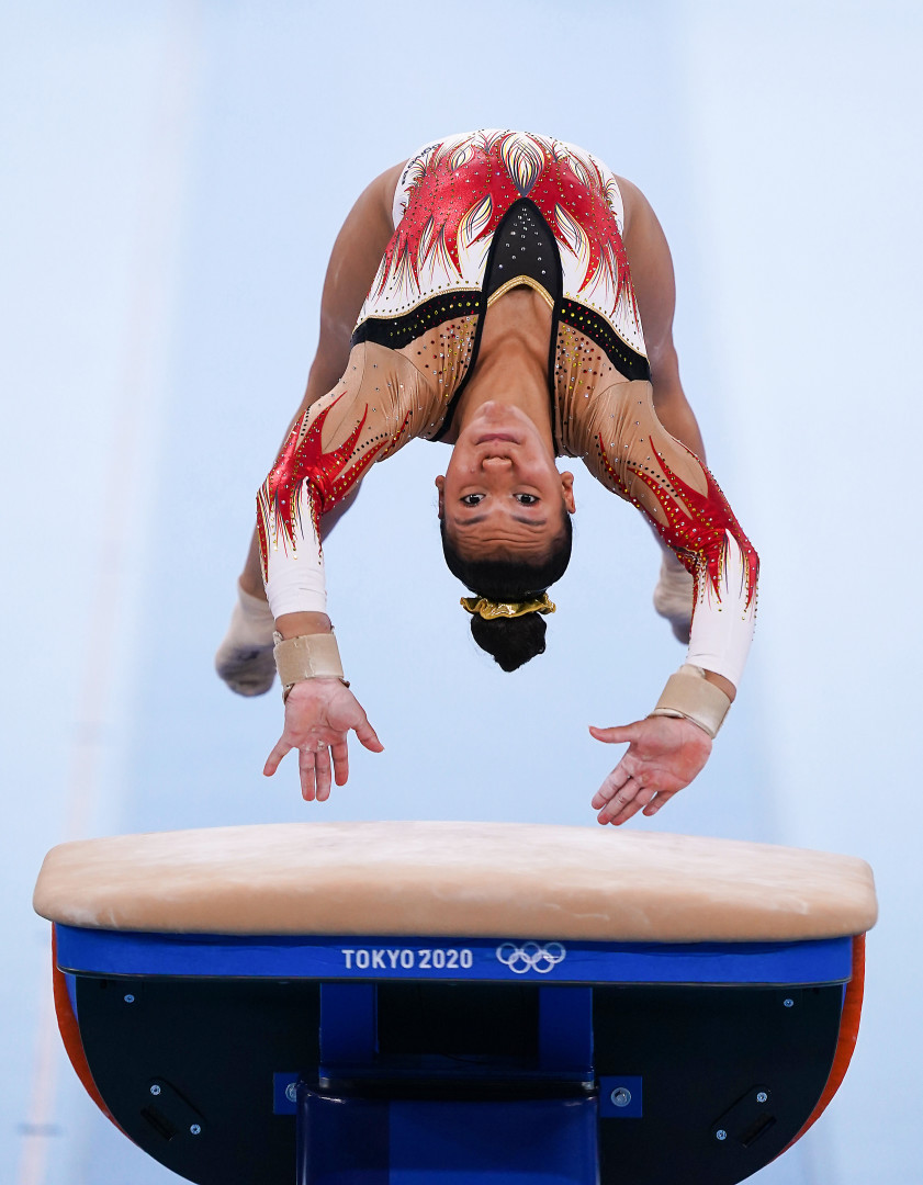 Gymnast mid back flip as she springs off a vault platform.