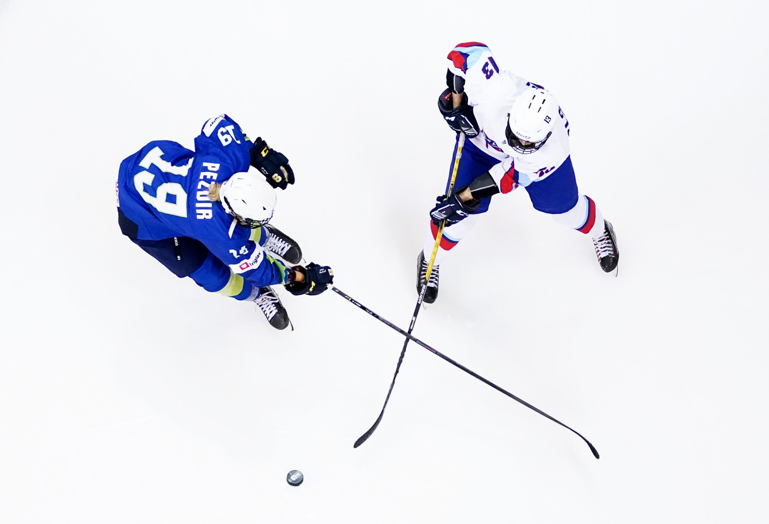 Two ice hockey players battling for the puck as their sticks create an 'X' shape.