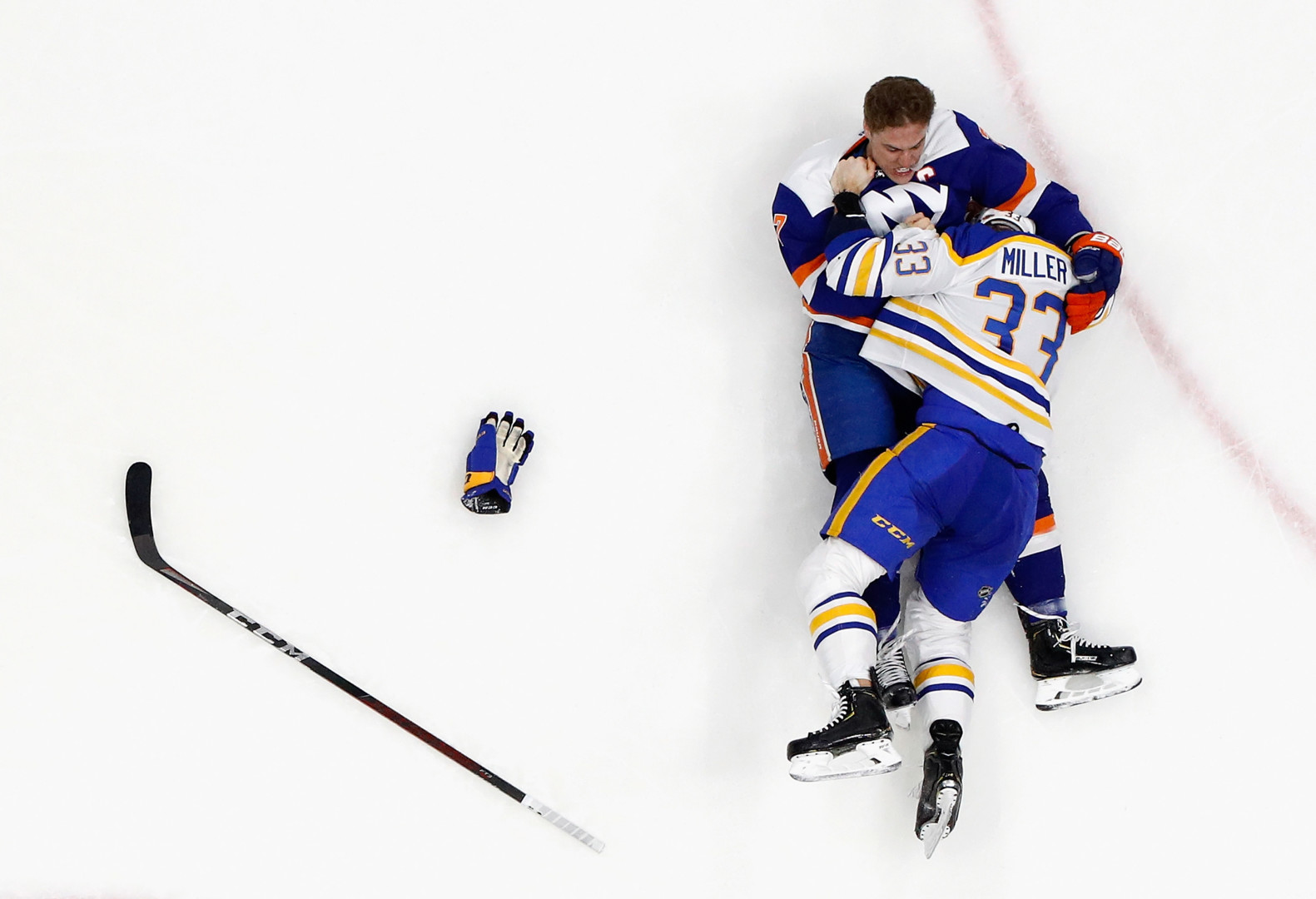 Two Ice Hockey players wrestling each other on the ice.
