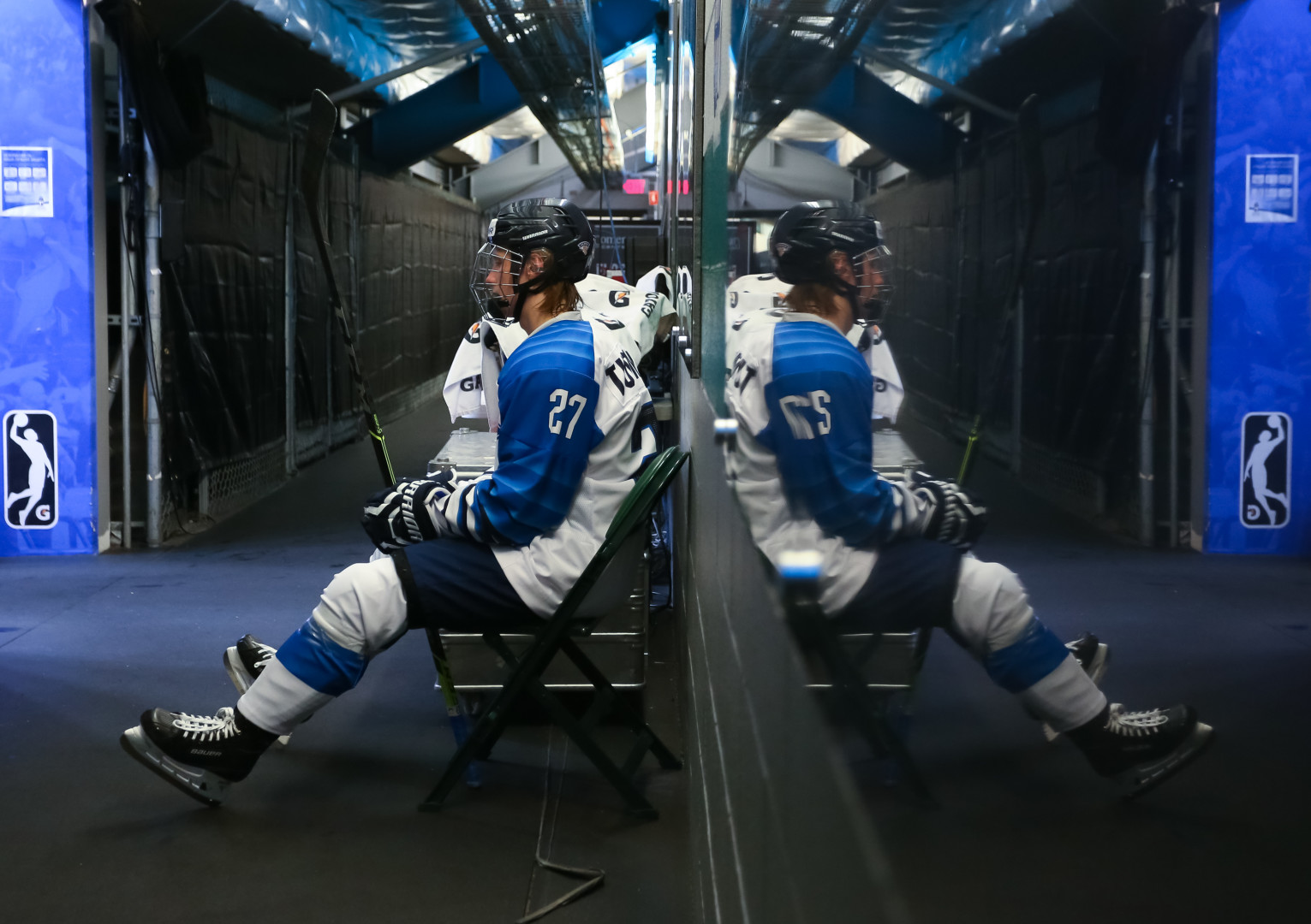 Split screen image of a Ice Hockey player sat back stage as his reflection backs onto the glass.