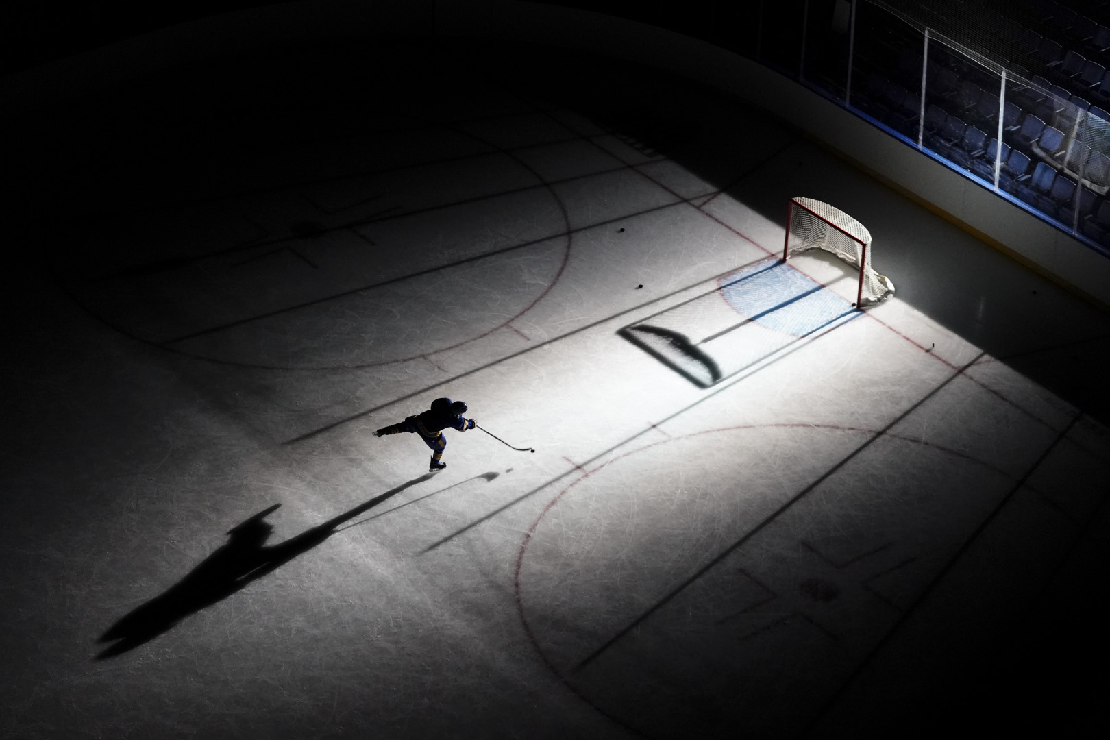 Ice Hockey player spotlighted and practising on the ice rink.