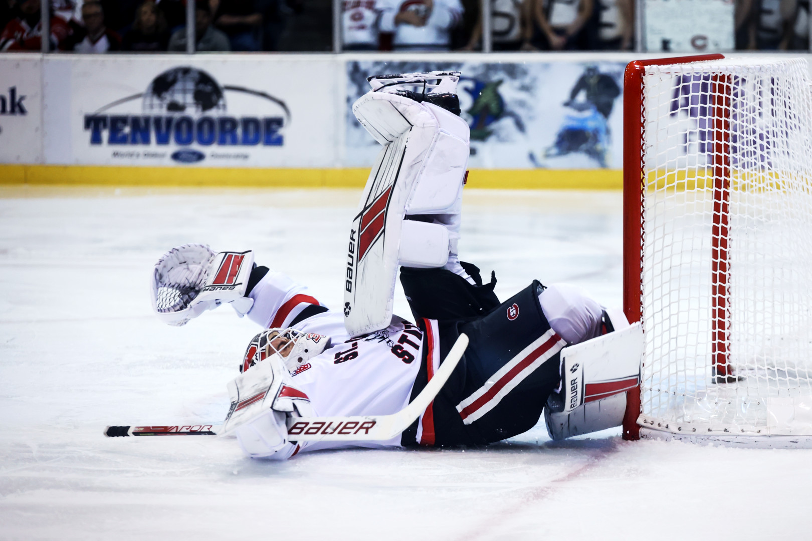 Ice Hockey goal keeper on their back in front of goal.