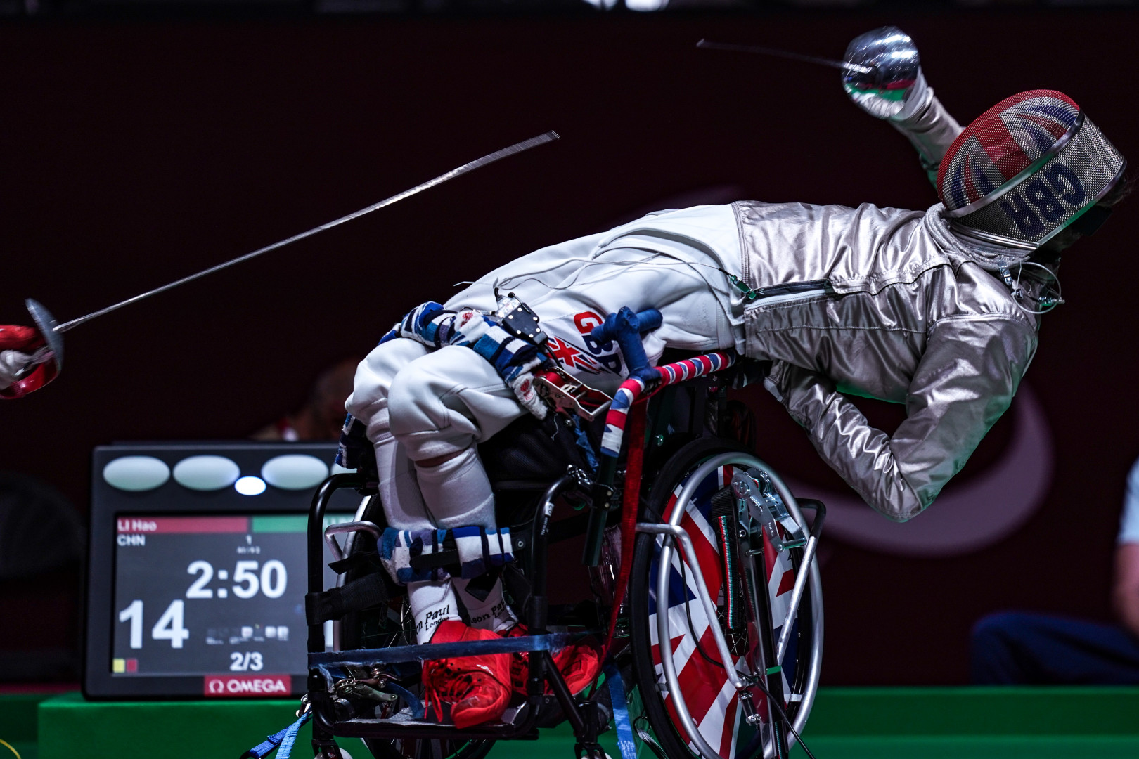 Paralympic wheelchair fencer dodging sword by bending backwards.