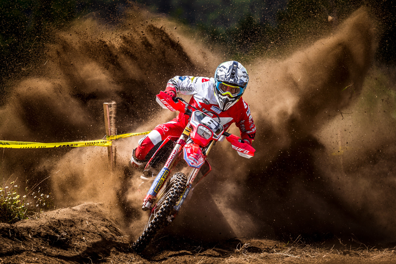 Motor cyclist skidding around the corner of a dirt track.