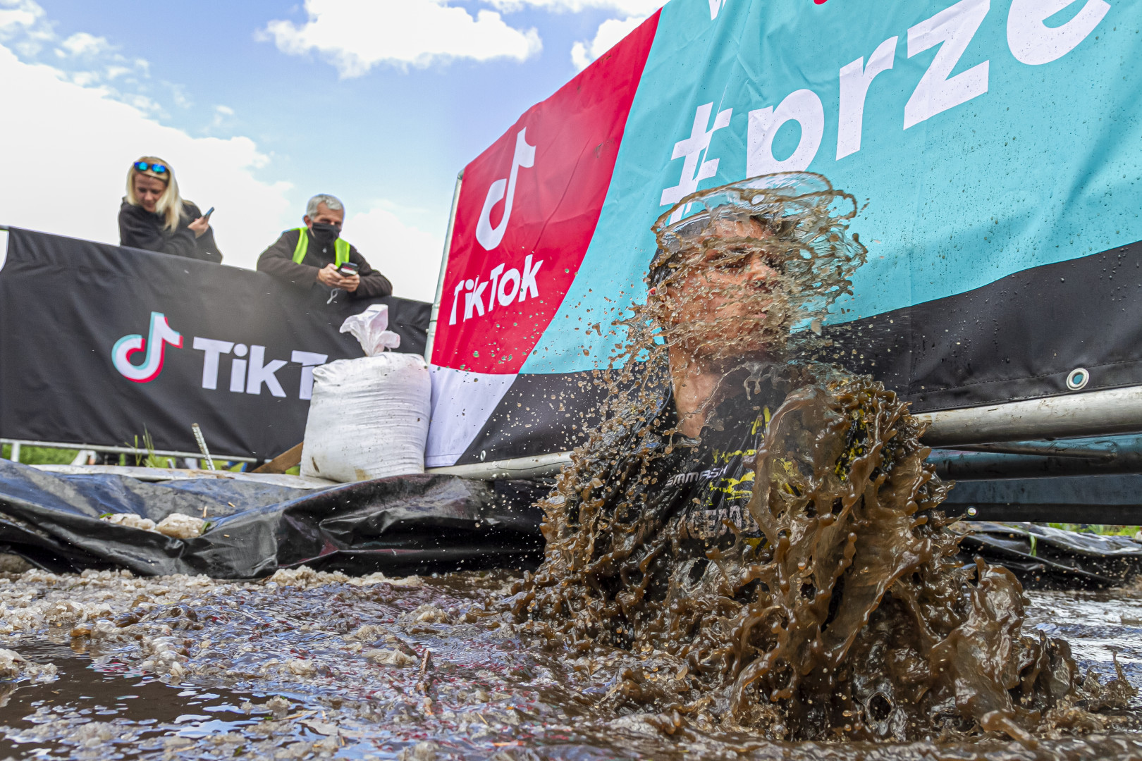 Man shaking off muddy water as onlookers watch on during Runmageddon.