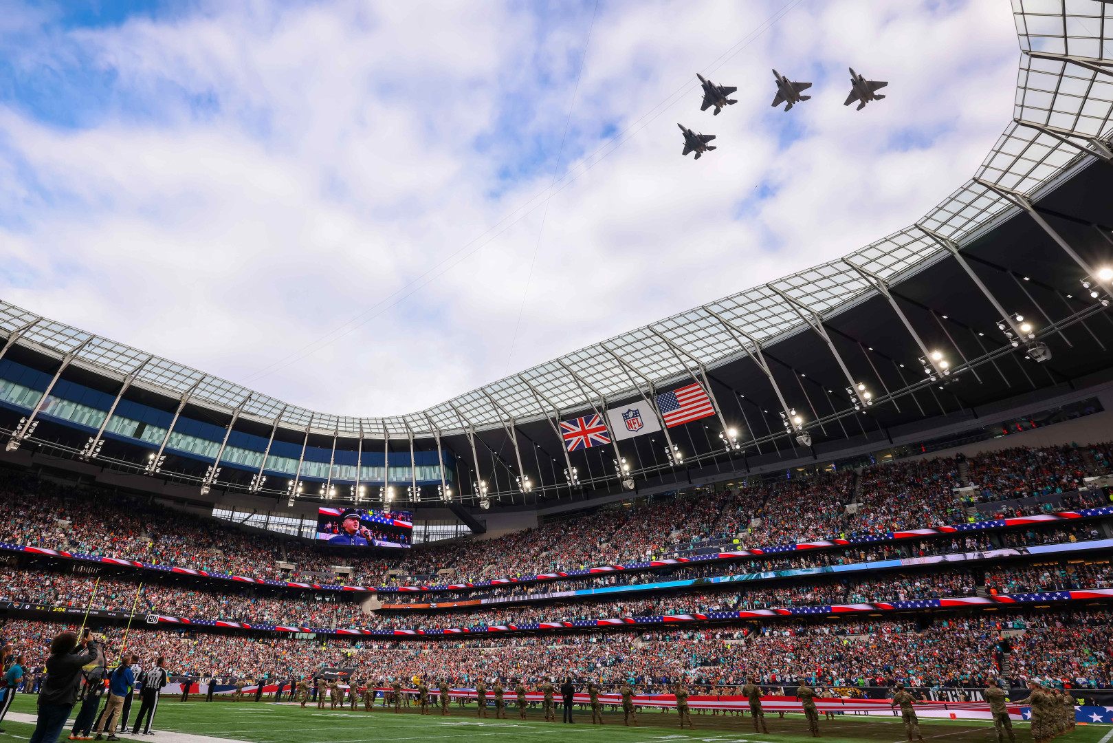 F15 Fly past at an NFL game as the army and a stadium full of people watch.