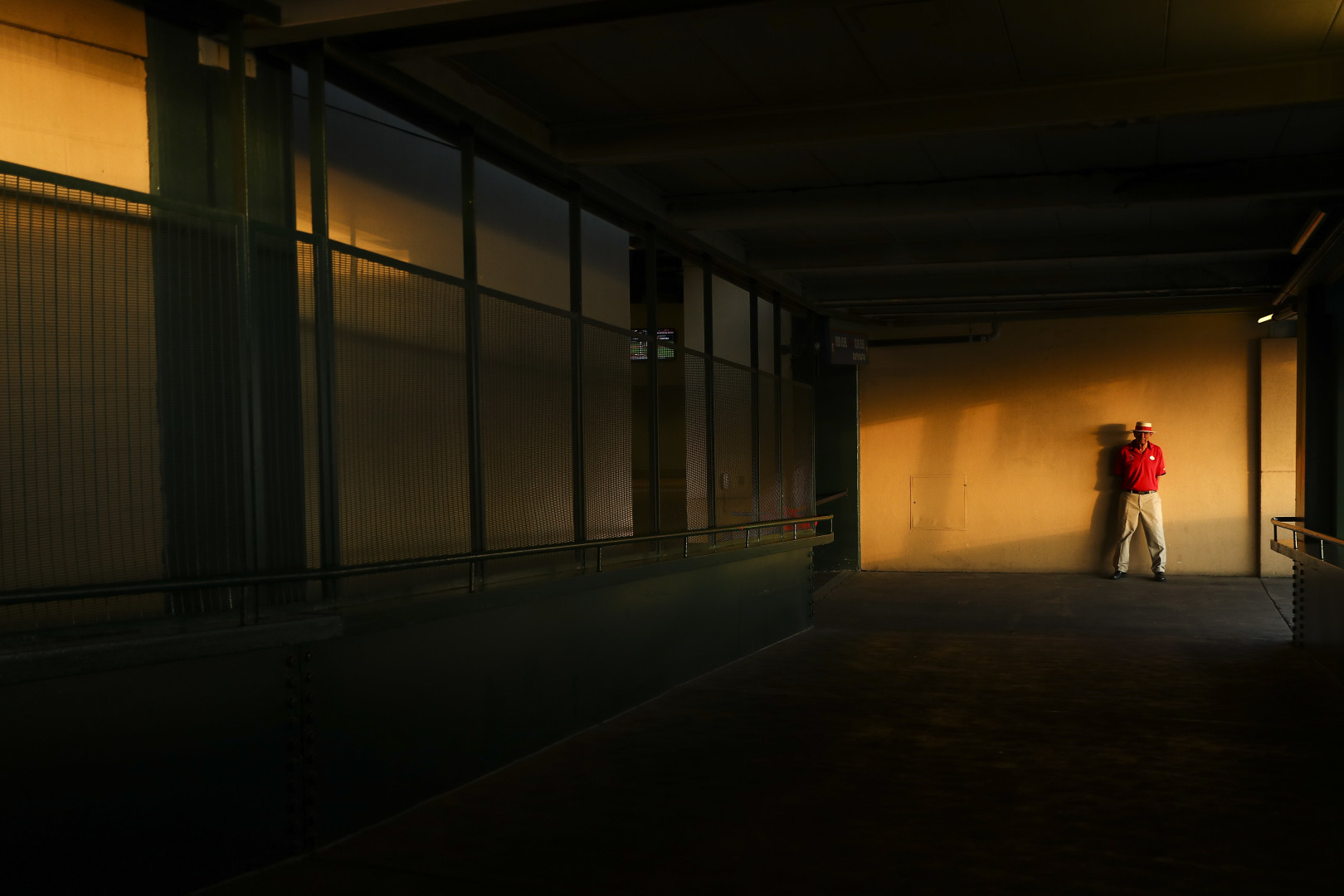 Sunset light spotlighted a warden in the concourse at a baseball stadium.