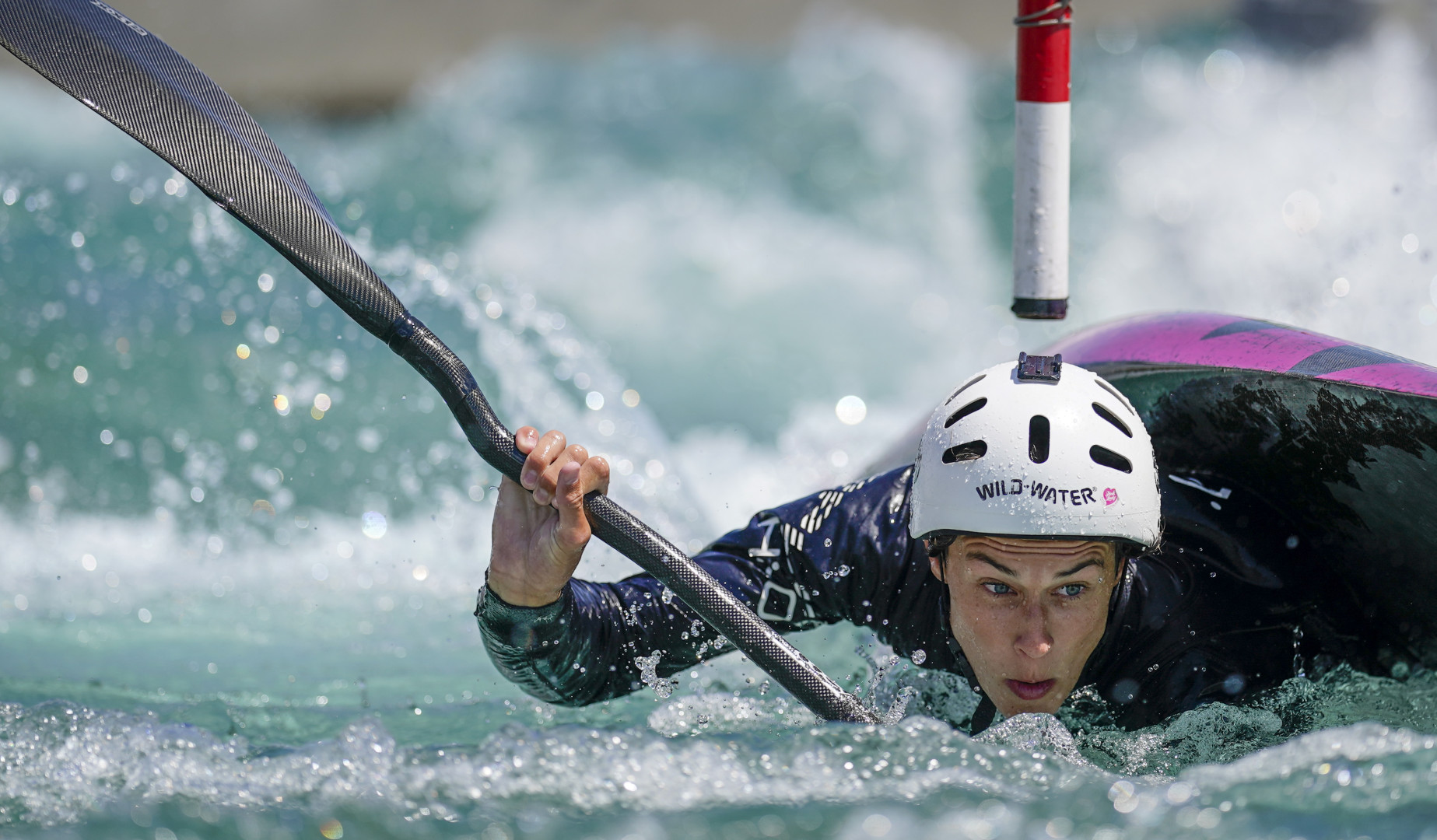 Female Slalom Canoeist moments before capsizing as she tries to avoid obstacle.
