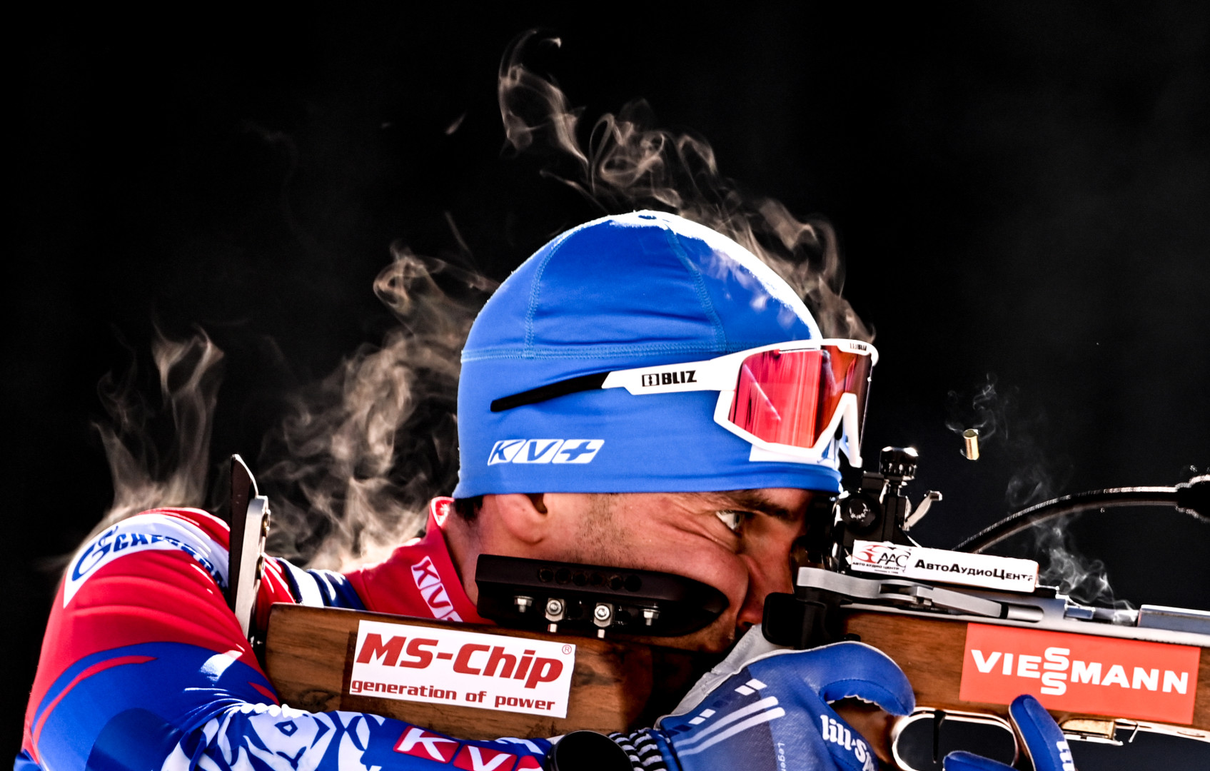 Close up head shot of a male Biathlete concentrated on his shot as heat rises from his body.